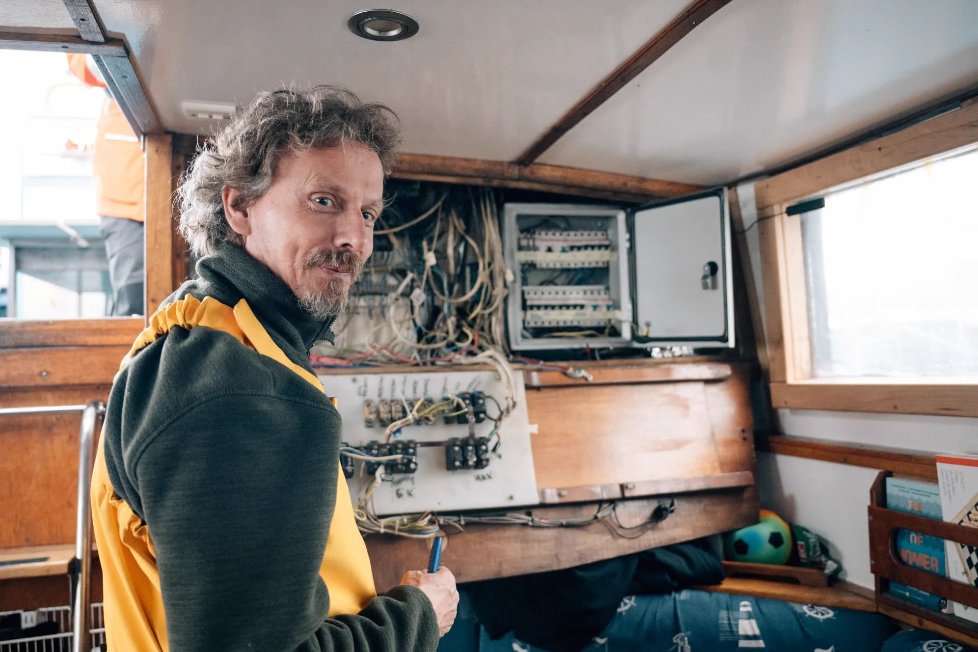 Crewmitglied vor der offenen Schalttafel an Bord des Segelschiffs